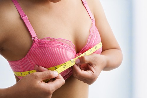 A woman measuring the size of her breasts after pregnancy Breast changes during pregnancy
